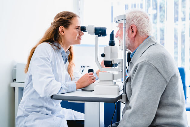 female eye doctor performing an eye exam on an elderly patient